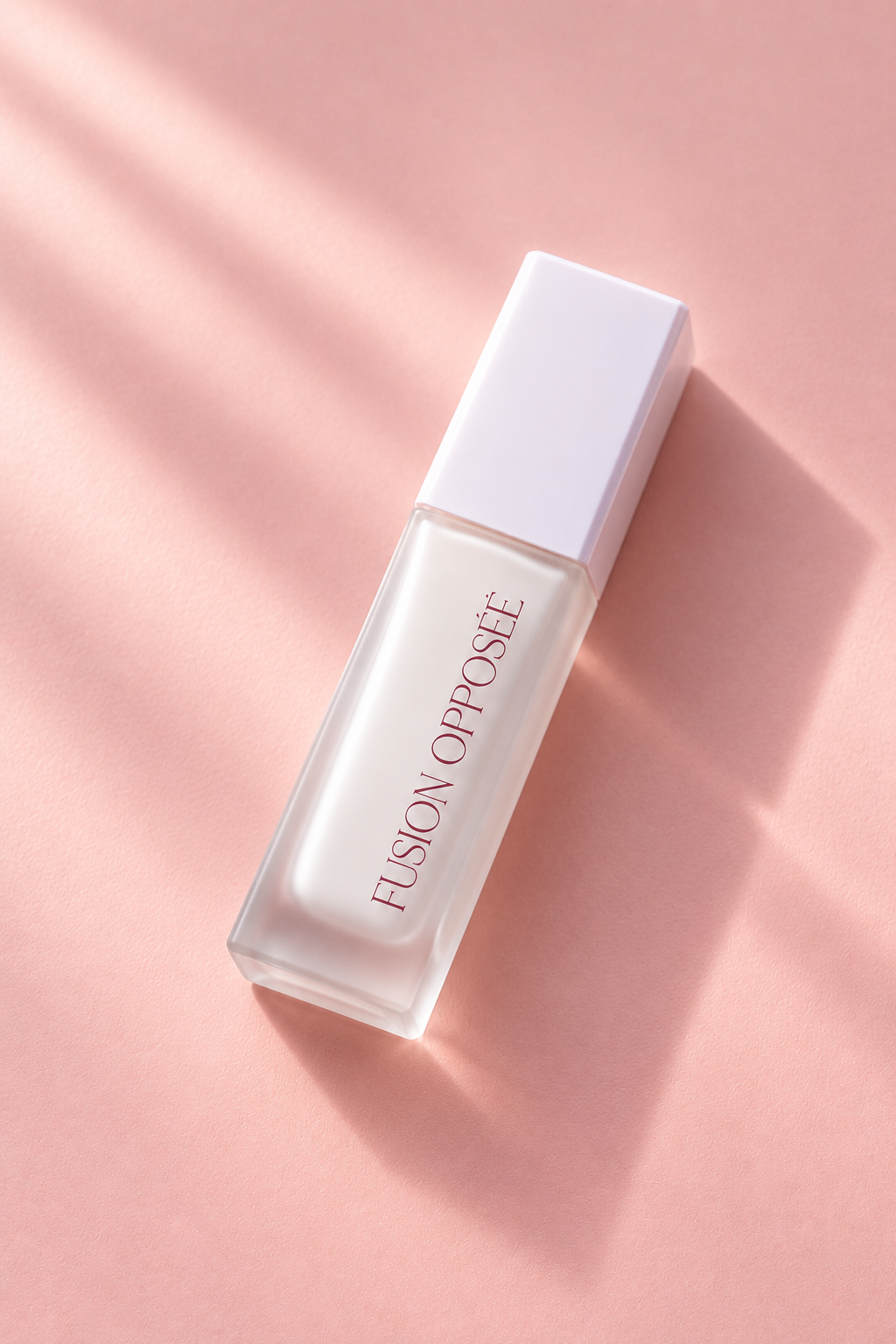 Flacon de fond de teint Fusion Opposée en verre dépoli, fermé avec son capuchon blanc et allongé en diagonale sur fond rose, éclairé par une lumière naturelle avec une ombre douce.