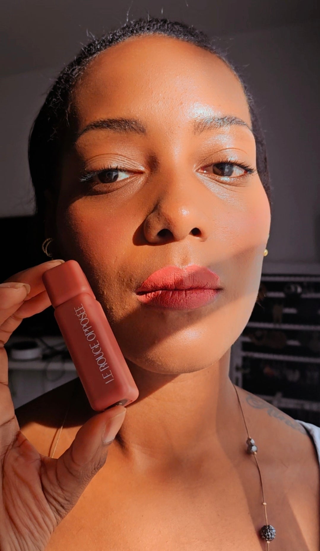 Femme portant Le Rouge Opposée et présentant le rouge à lèvres près de son visage