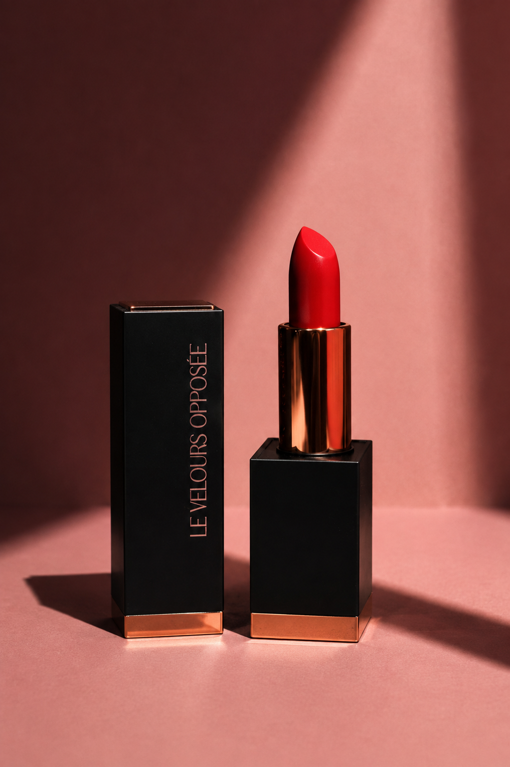 Le Velours Opposée ouvert avec rouge à lèvres rouge, écrin noir et détails dorés sur fond rose