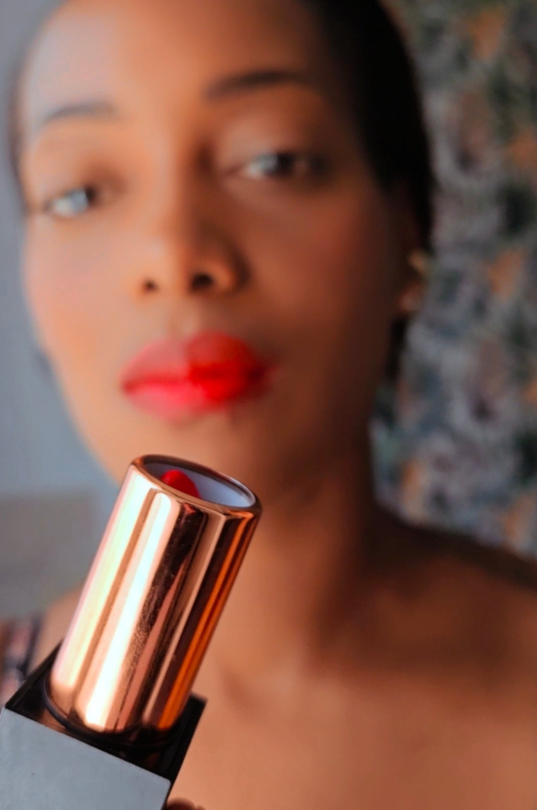 Femme portant Le Velours Opposée rouge et présentant le rouge à lèvres près de son visage