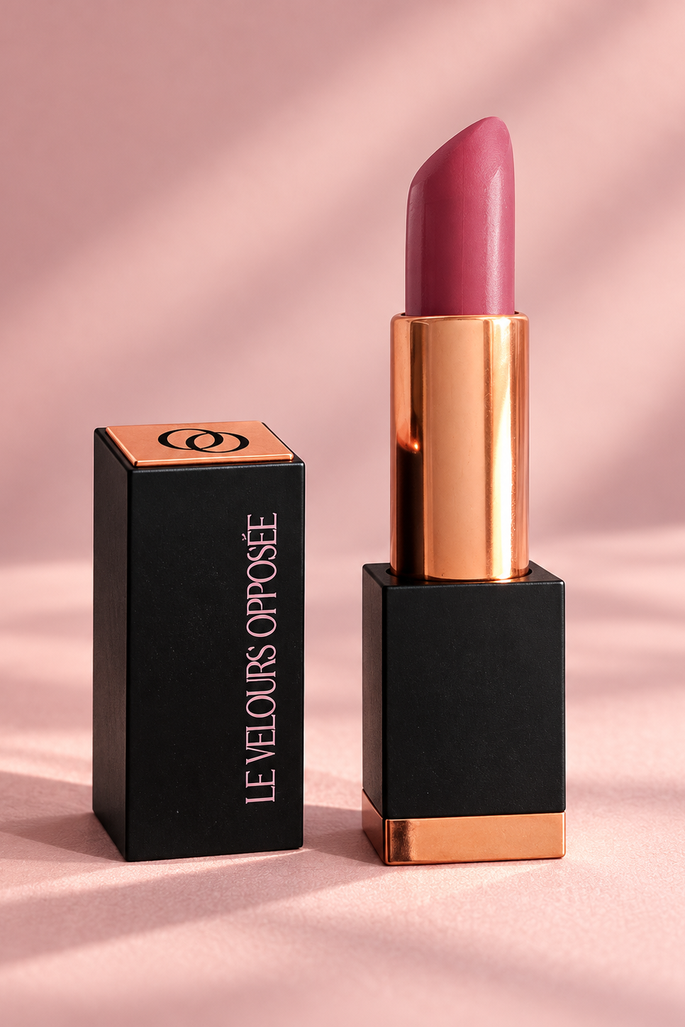 Le Velours Opposée ouvert avec rouge à lèvres rouge, écrin noir et détails dorés sur fond rose